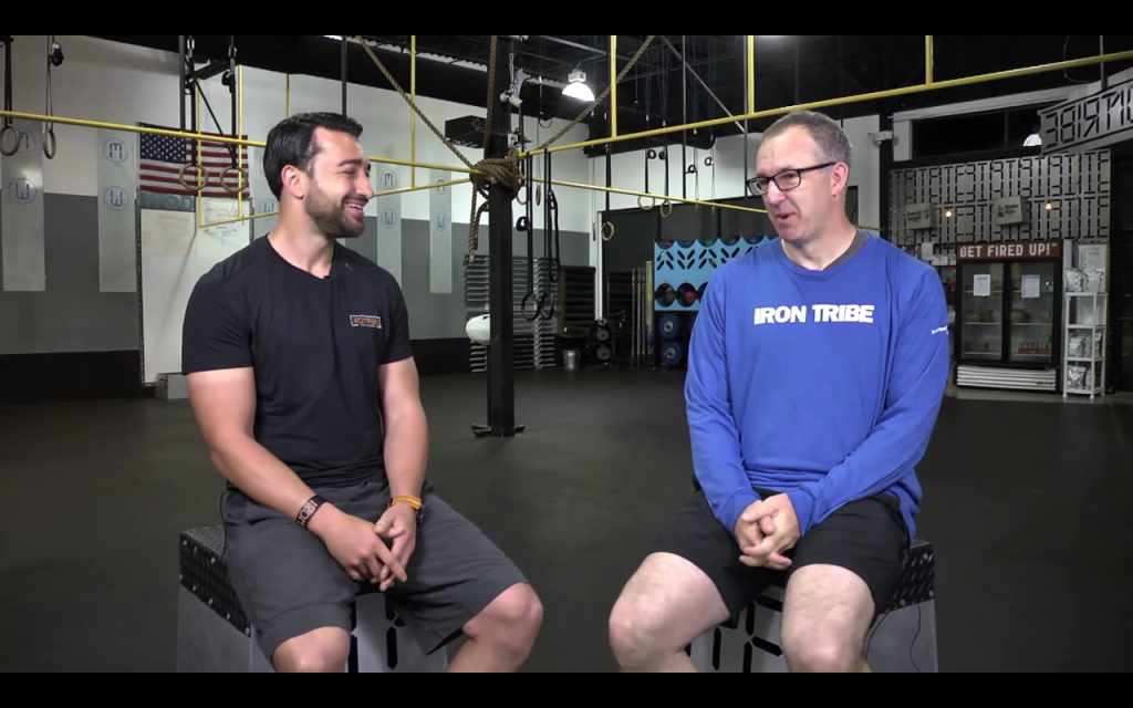 SEC Commissioner Greg Sankey talks with Iron Tribe Fitness President Jim Cavale during a testimonial. (Photo: Screenshot from Iron Tribe Fitness video) 